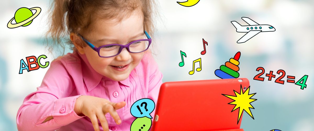 Child sitting with tablet computer and learning or playing with great interest