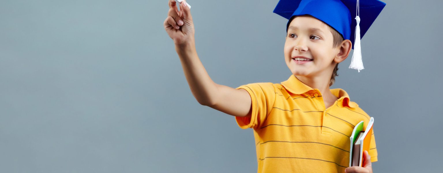 Portrait of cute schoolkid writing with chalk on imaginary blackboard